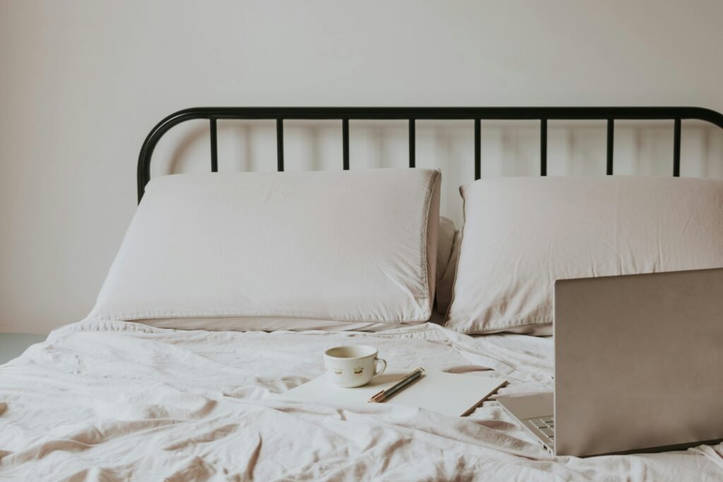 How to Fix Night Shift Sleep Problems: 7 Effective Solutions for Better Rest 6 Minimalist home office setup with laptop on bed, coffee cup, and notes for a comfortable work environment.