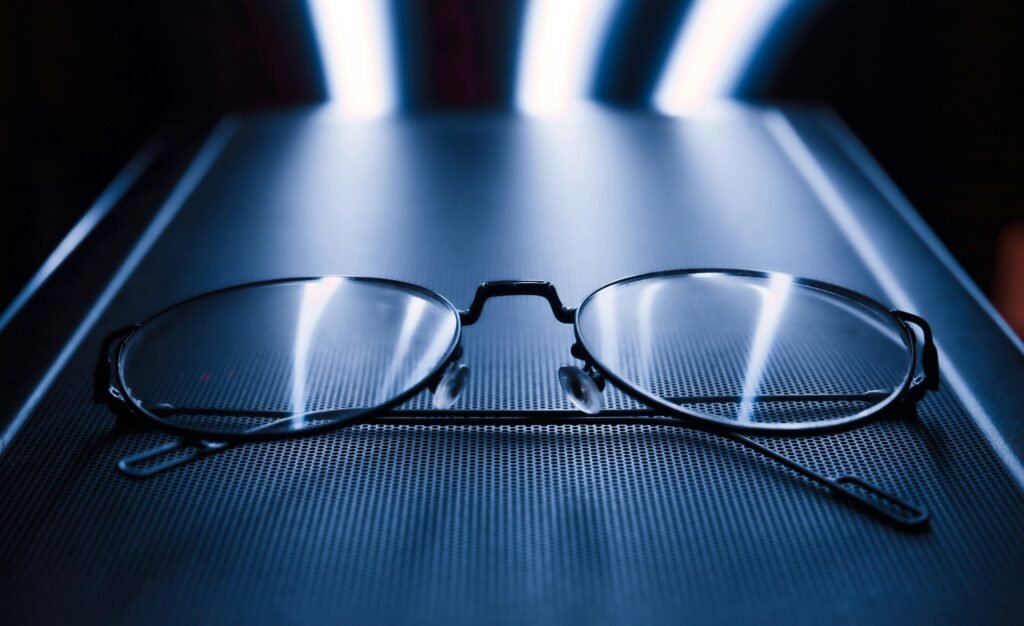 How to Fix Night Shift Sleep Problems: 7 Effective Solutions for Better Rest 7 Close-up shot of eyeglasses with a dark blue background and reflective blue light.