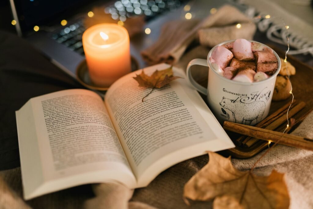 What to Do When Night Shift Insomnia Won't Go Away: Breaking the Cycle 5 A warm autumn setup featuring a book, hot chocolate with marshmallows, and a lit candle.