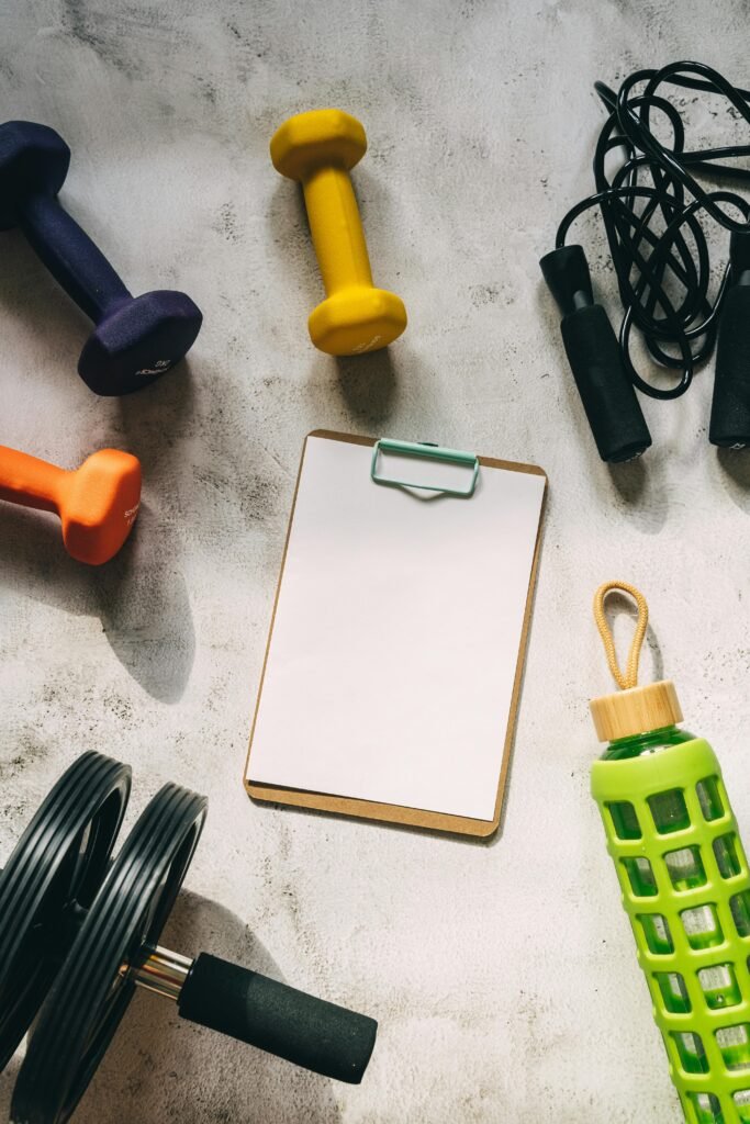 Home 3 Flat lay of colorful dumbbells, fitness gear, and blank clipboard for workout planning.