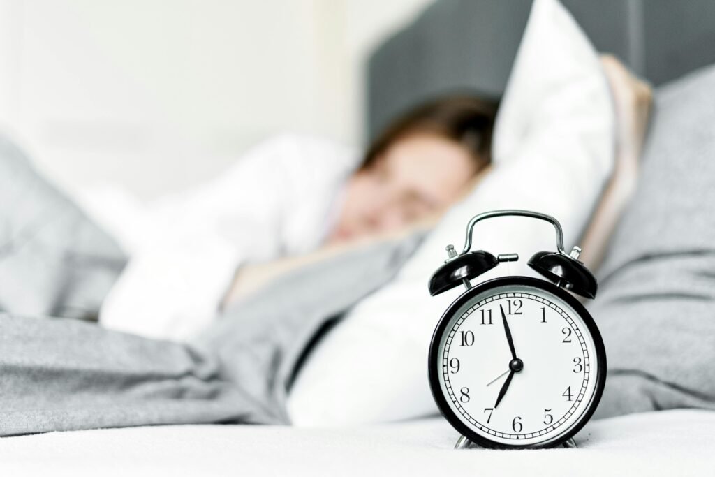 How to Fix Night Shift Sleep Problems: 7 Effective Solutions for Better Rest 2 A retro alarm clock sits by a sleeping woman in a cozy bedroom setting.