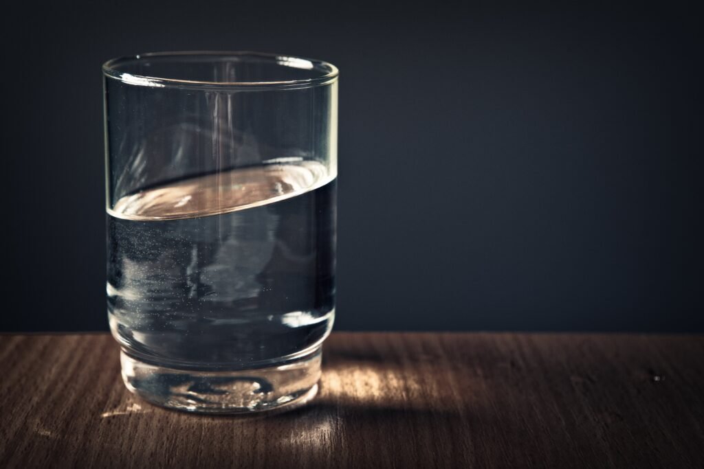 How To Stay Energized on Night Shifts: A Science-Backed Guide 6 A clear glass of water sitting on a wooden table against a dark background.