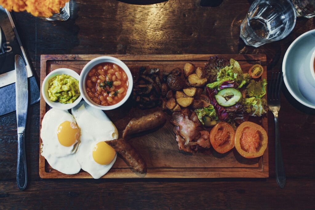 Stop Night Shift Weight Gain: 8 Proven Metabolism Boosters 3 Top view of delicious fried eggs and vegetables with sausages and beans on wooden tray with fork and knife