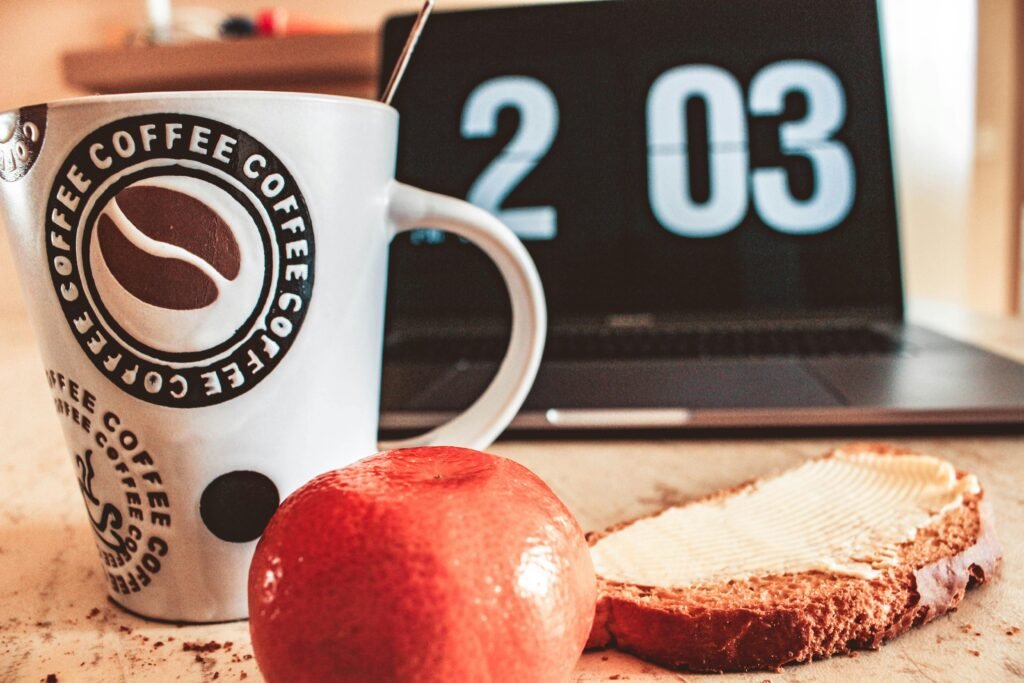 Stop Night Shift Weight Gain: 8 Proven Metabolism Boosters 2 A cozy breakfast setup with coffee, bread, and fruit next to a laptop.
