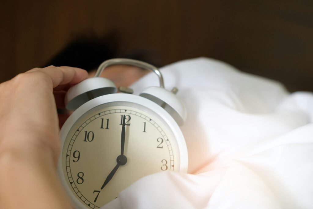 How to Manage Night Shift Digestive Problems 9 A close-up of a hand reaching for a ringing alarm clock, symbolizing waking up in the morning.