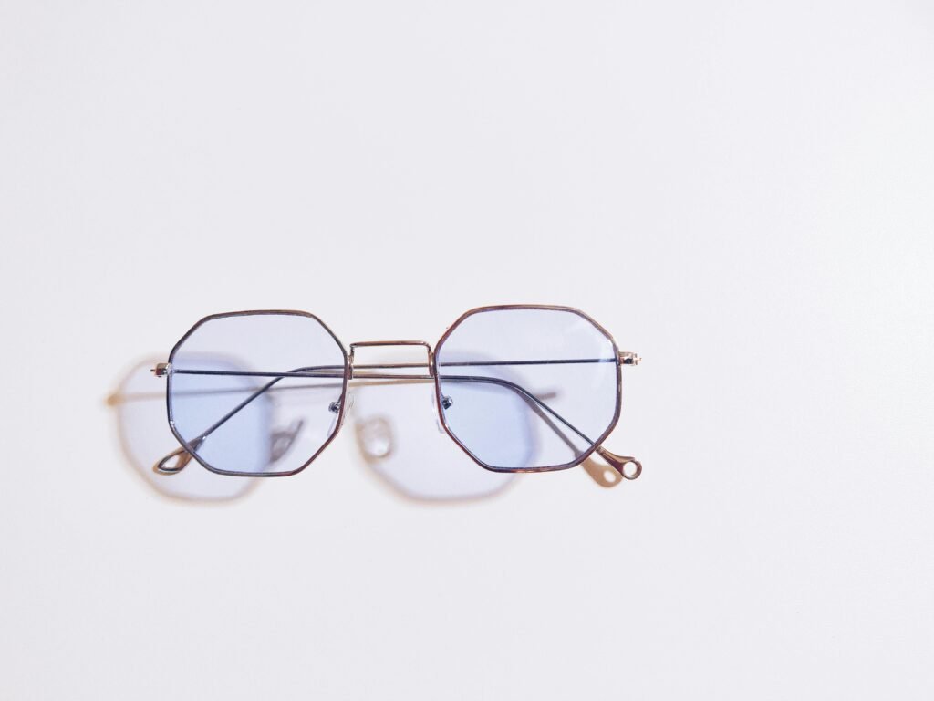 Essential Products for Night Shift Workers 4 Sleek blue tinted eyeglasses casting shadows on a minimalist white background, perfect for design inspiration.