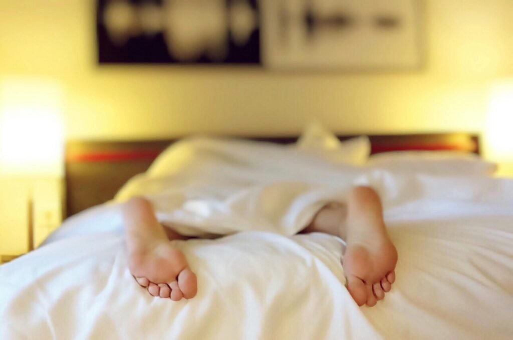 What to Do About Night Shift Memory Problems and Cognitive Decline 4 A person relaxing on a bed with feet under white sheets, conveying serenity.