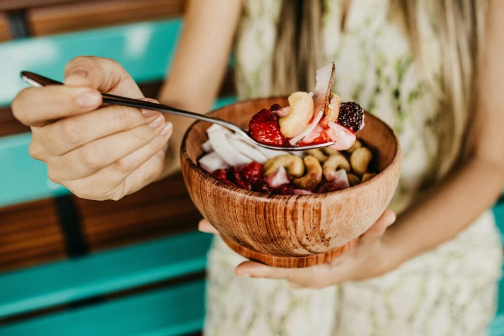Mastering Sleep in Your Night Shift Lifestyle: A Complete Guide to Overcoming Sleep Disorders 4 Healthy acai smoothie bowl with fresh berries and nuts held in a wooden bowl.