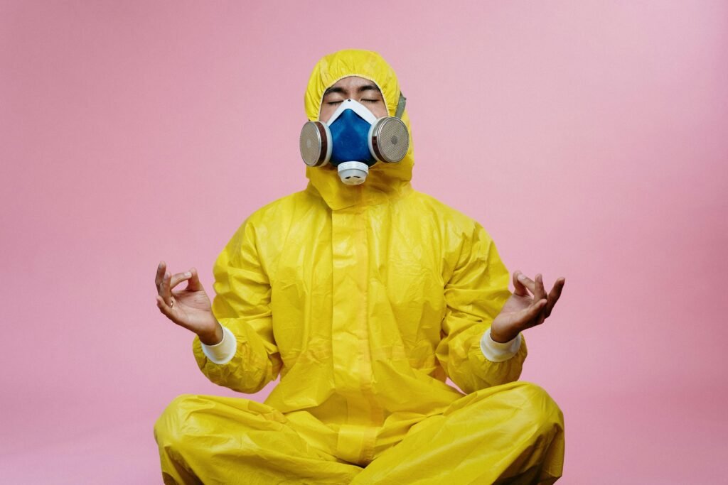 How to Build Immunity Against Frequent Night Shift Illnesses 10 Man in protective suit and respirator practicing meditation against pink backdrop.