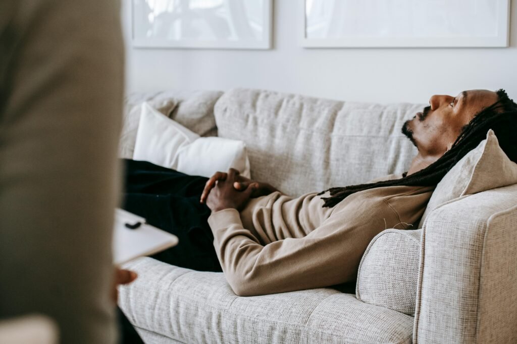 Mastering Sleep in Your Night Shift Lifestyle: A Complete Guide to Overcoming Sleep Disorders 6 Man in therapy session lying on sofa, conversing with therapist in a relaxed indoor setting.
