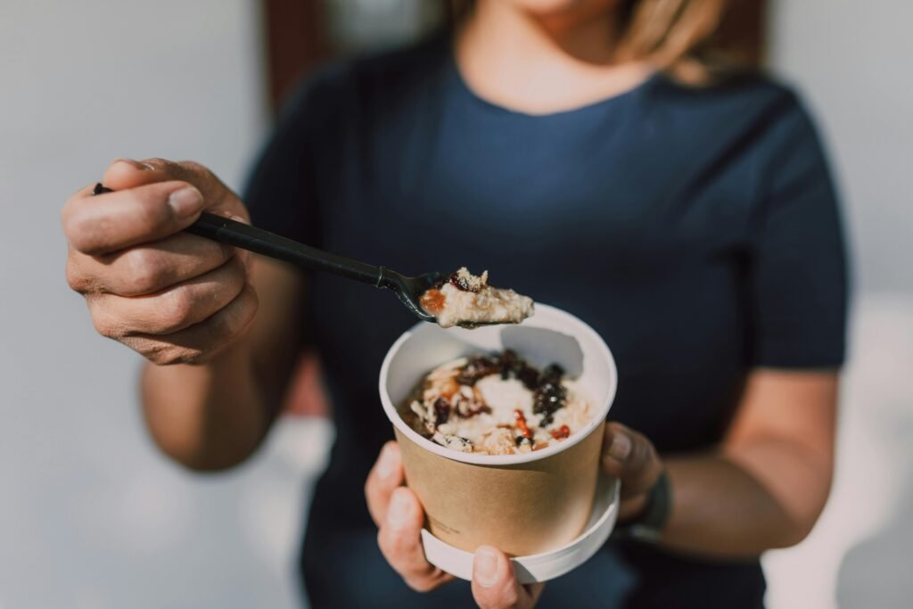 How to Manage Night Shift Digestive Problems 1 Close-up of a person holding a bowl of vegan oatmeal topped with fruits.