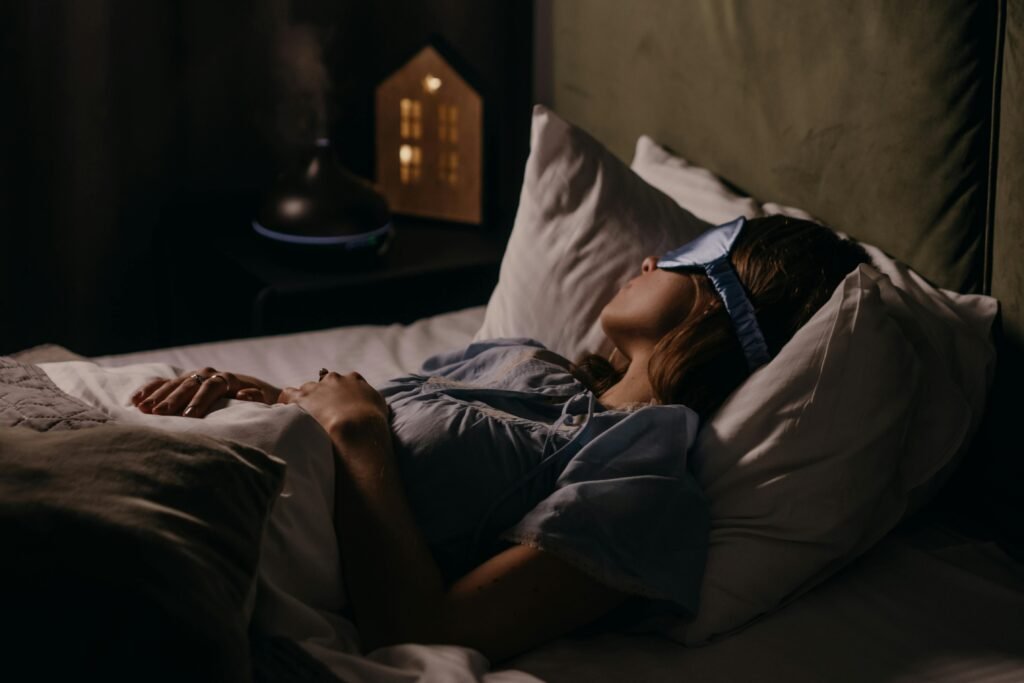 Essential Products for Night Shift Workers 2 A woman peacefully sleeping with an eye mask in a dimly lit bedroom, capturing a serene bedtime atmosphere.