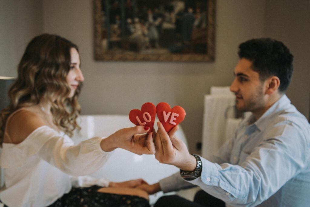Night Shift and Relationships: Communication Solutions That Work 7 A couple sharing a romantic moment indoors, holding heart-shaped love symbols, enhancing a Valentine's Day feel.