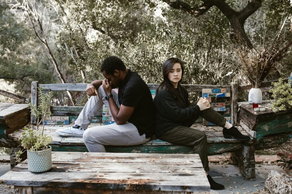 Night Shift and Relationships: Communication Solutions That Work 1 A couple sits back to back on a wooden bench, indicating a disagreement or breakup.