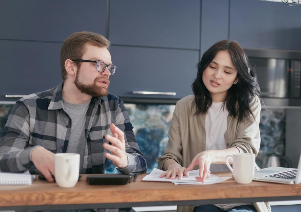 Night Shift and Relationships: Communication Solutions That Work 6 A young couple discusses financial documents at a cozy home setting, expressing concern.