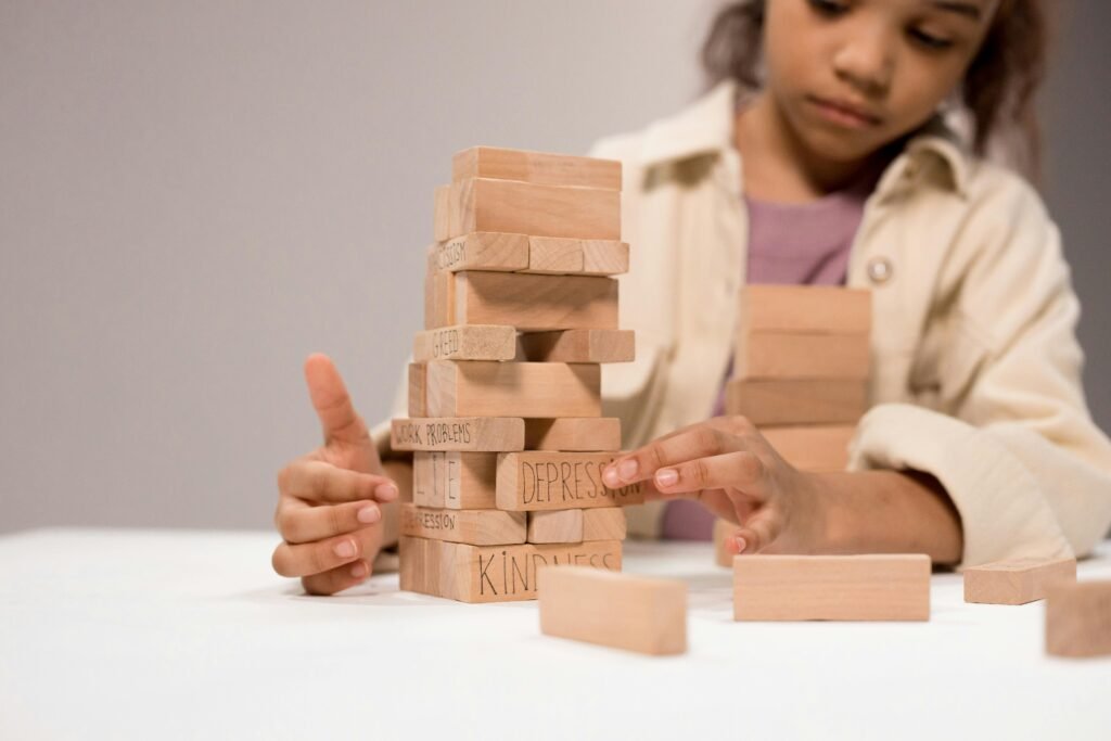 What to Do About Night Shift Depression: Recognition and Self-Care Steps 3 A child thoughtfully stacks wooden blocks with words like 'depression' and 'kindness.'