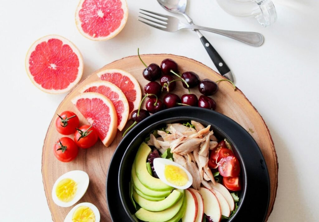How to Build Immunity Against Frequent Night Shift Illnesses 4 A vibrant breakfast flat lay featuring a mix of fruits, avocado, eggs, tomatoes, and sliced meats on a wooden platter.