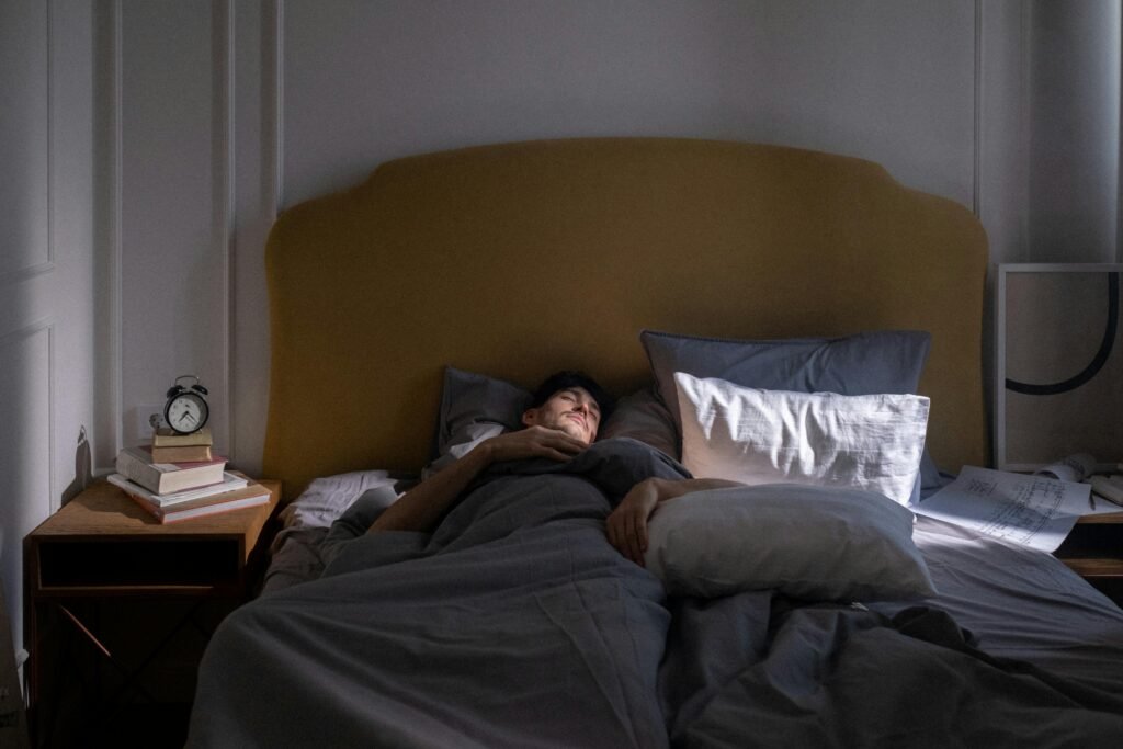 How to Combat Night Shift Skin Problems 7 A man sleeping in a cozy bed with soft morning sunlight filtering in.