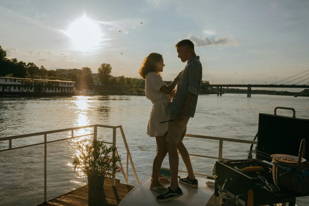 Night Shift and Relationships: Communication Solutions That Work 5 A couple enjoys a romantic moment on a yacht with a stunning sunset over the river, evoking feelings of love and adventure.