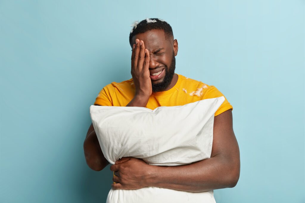 young man with feathers t shirt holding pillow