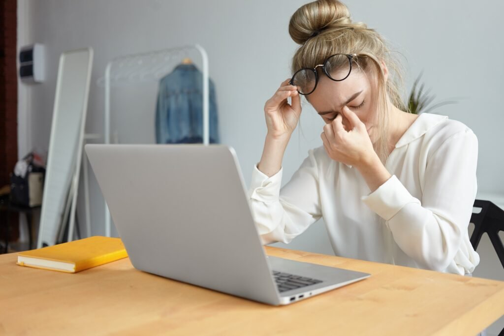 modern technology job people concept portrait tired young female employee with hair bun taking off eyeglasses massaging her nose bridge feeling stressed because lot work 1