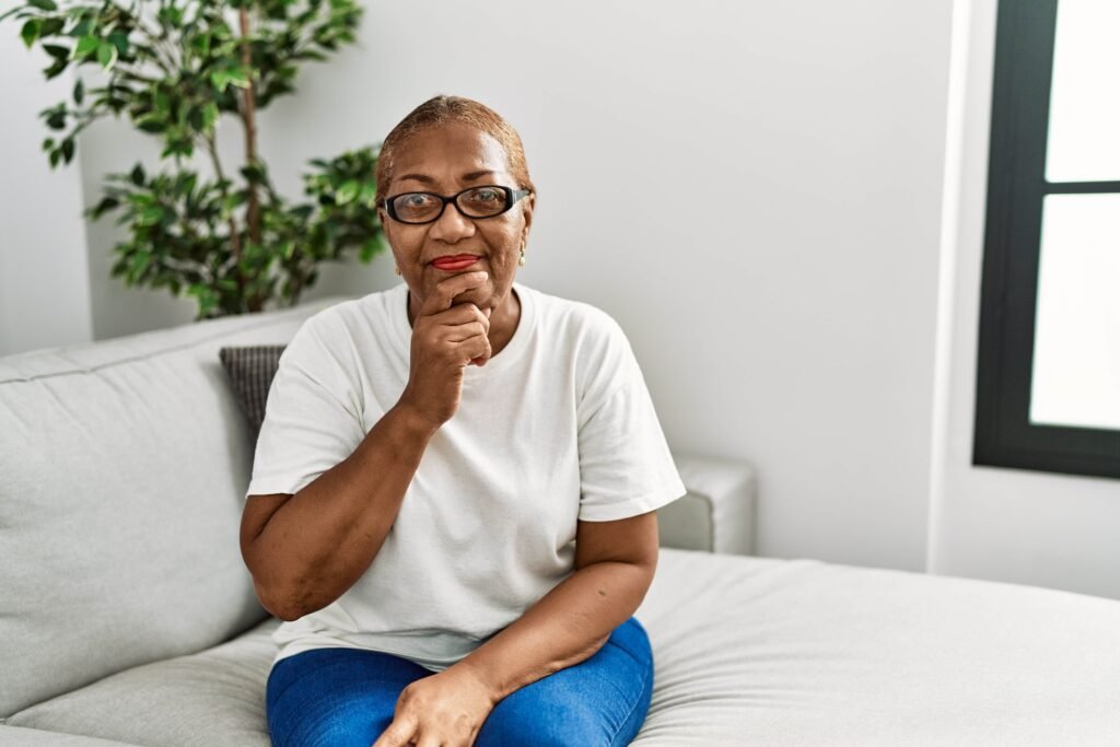 mature hispanic woman sitting sofa home looking confident camera with smile with crossed arms hand raised chin thinking positive 1