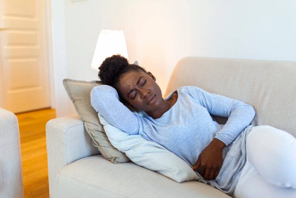 woman lying sofa looking sick living room beautiful young woman lying bed holding hands her stomach woman having painful stomachache bed menstrual period 1